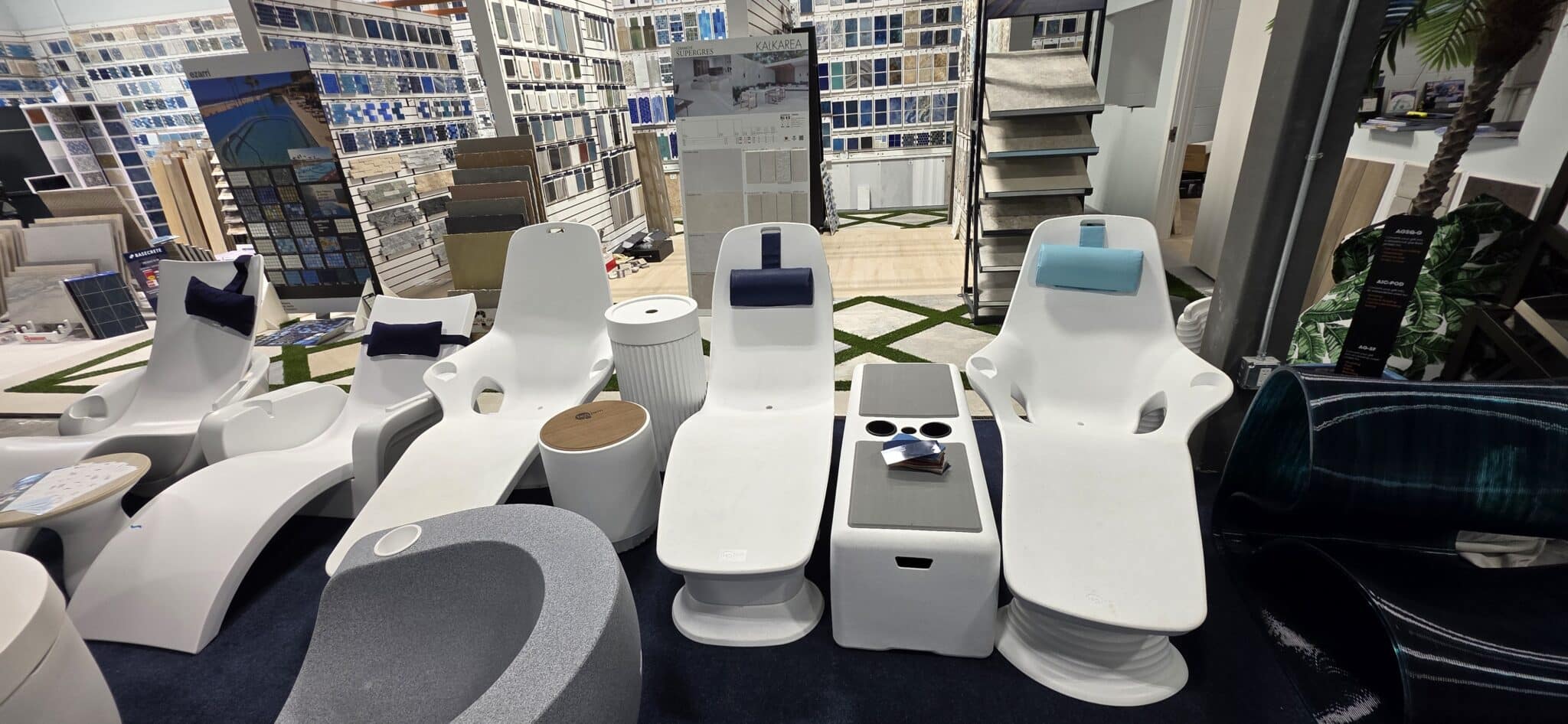White pool loungers with navy and turquoise headrests beside tables at the Jupiter showroom