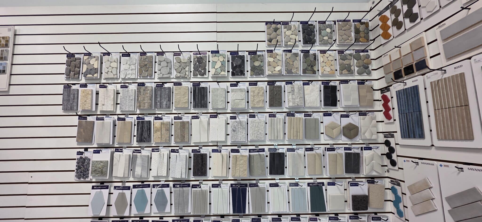 Pool tile samples and finish options on the material selection wall at Innovative Outdoor Living's Jupiter showroom
