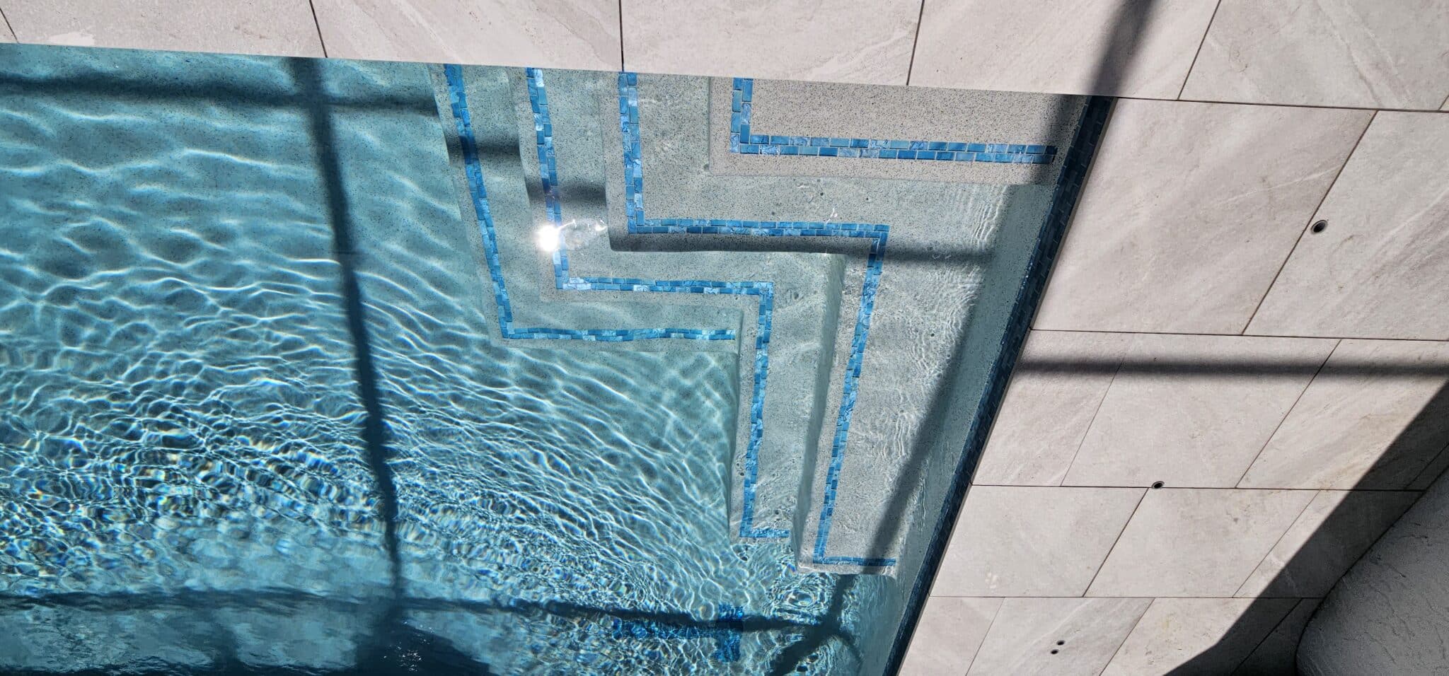 Submerged entry steps with blue tile accents in a completed Jupiter Farms pool