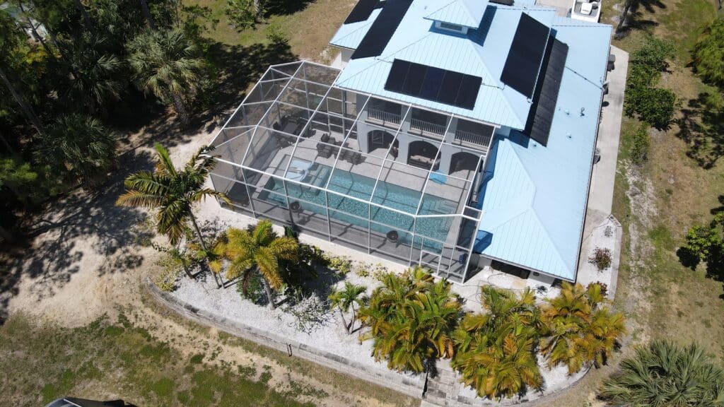 Aerial view of a completed Jupiter Farms swimming pool, screen enclosure, deck and palm landscaping