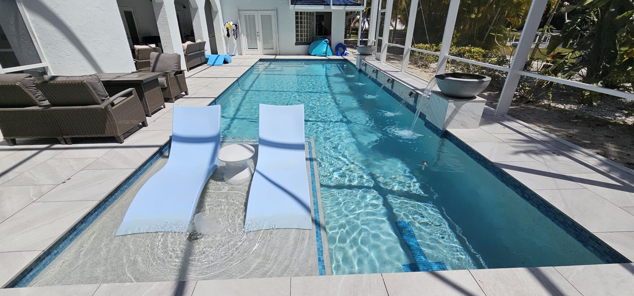 Two white loungers on a shallow sun shelf beside a rectangular Jupiter Farms swimming pool