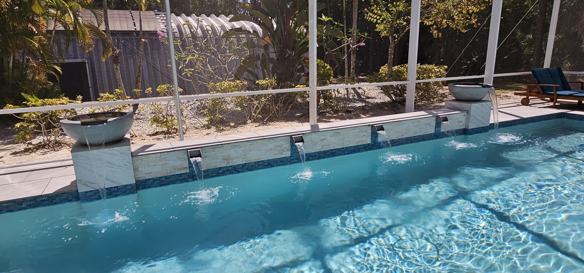 Raised pool wall with water features and tropical planting at a Jupiter Farms pool