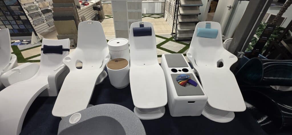 Three white Tenjam reclining loungers with blue headrests at Innovative Outdoor Living's Jupiter showroom